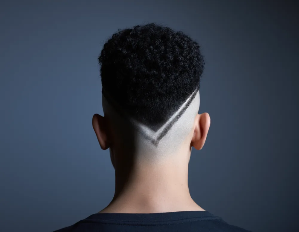 Macro photograph of the same style of head after a skin fade, with a smooth gradient from bare skin into dense coily texture and a sharp shaped nape line